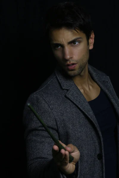 Handsome young wizard holding a magic wand — Stock Photo, Image