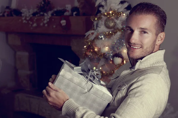 Mladý muž s blond vlasy drží vánoční dárek — Stock fotografie