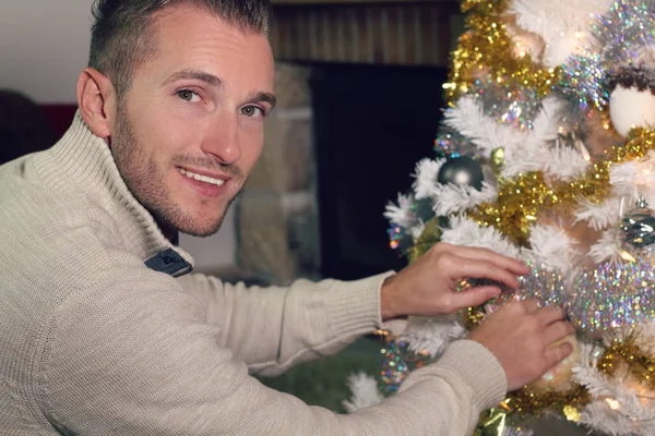 Joven hombre rubio decorando un árbol de Navidad — Foto de Stock