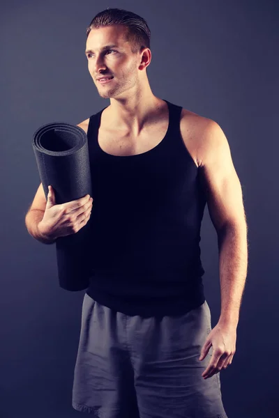 Yakışıklı adam bir fitness mat holding — Stok fotoğraf