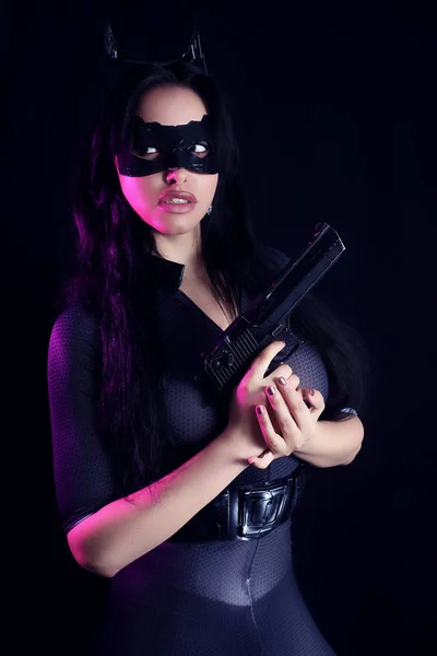Mooi meisje een catsuit houdt een pistool dragen — Stockfoto