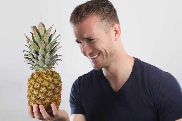 年轻男子笑着拿着一只菠萝 — 图库照片