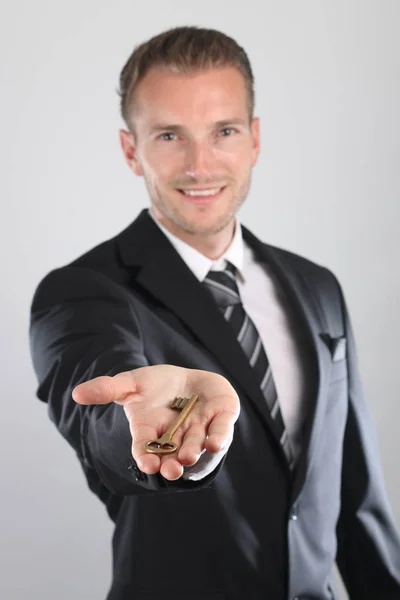 Un bel homme souriant tenant une clé pour la maison — Photo