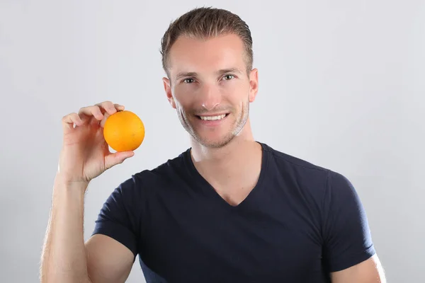 Yakışıklı adam portakal gösteriyor. — Stok fotoğraf