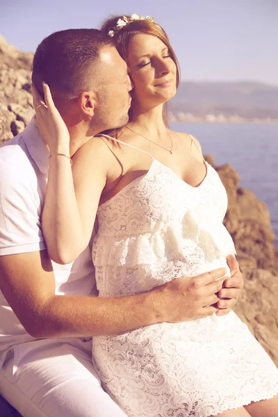 Casal grávida no amor beijando na praia — Fotografia de Stock