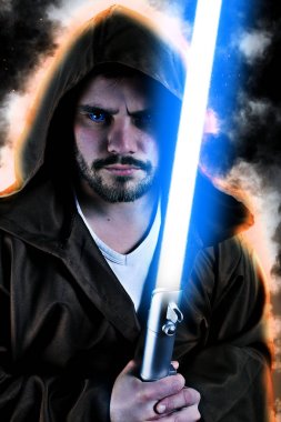 bir lazer kılıcı tutan kahverengi kukuletalı pelerin ile genç savaşçı 