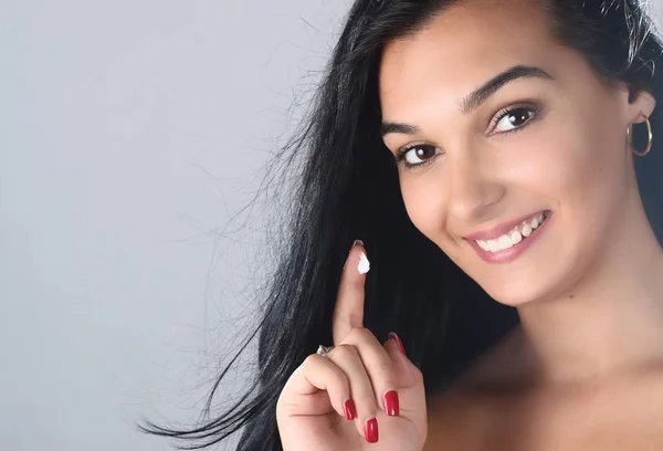 Retrato de mujer joven aplicando un poco de crema en su cara para el cuidado de la piel —  Fotos de Stock