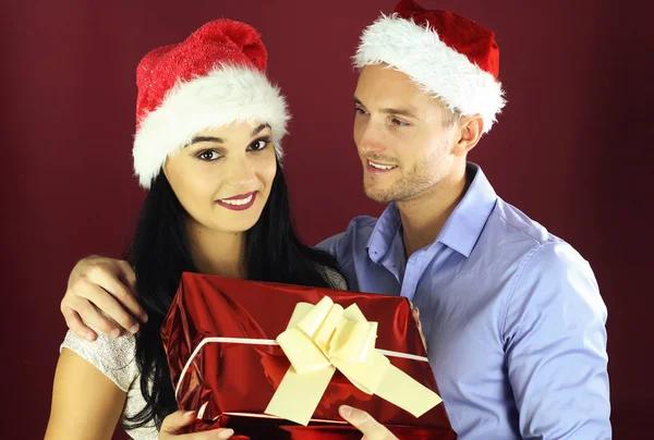 Junger Mann Überrascht Seine Freundin Mit Einem Weihnachtsgeschenk Auf Rotem — Stockfoto