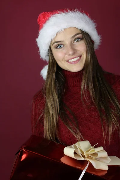 美丽的年轻女子举行圣诞礼物在红色背景 — 图库照片