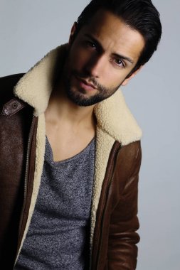 Beyaz bir arka plan üzerinde bir süet kürk giyen yakışıklı adam 