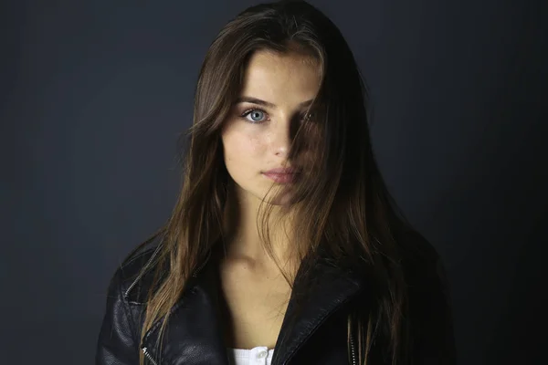 Hermosa adolescente mirando la cámara. Chica de moda con una chaqueta de cuero negro en el estudio —  Fotos de Stock