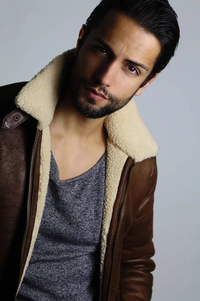 Beyaz bir arka plan üzerinde bir süet kürk giyen yakışıklı adam 