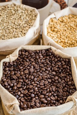 Yeşil ve kahverengi kahve çekirdekleri kavrulmamış ve siyah kahve çekirdekleri çuvalda.