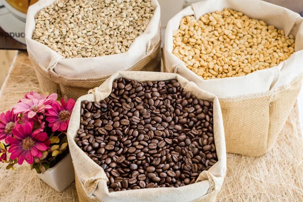 Yeşil ve kahverengi kahve çekirdekleri kavrulmamış ve siyah kahve çekirdekleri çuvalda.