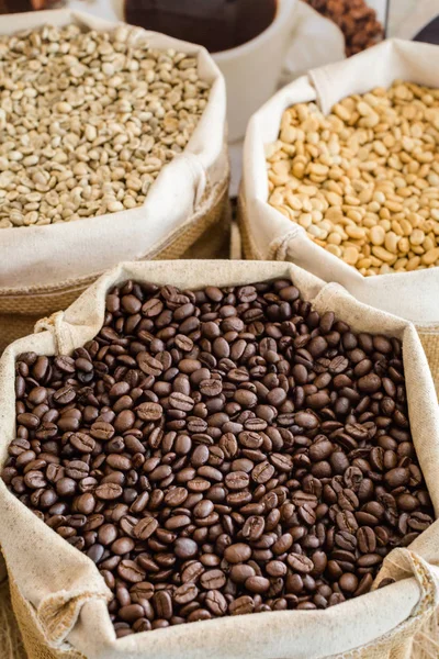 Yeşil ve kahverengi kahve çekirdekleri kavrulmamış ve siyah kahve çekirdekleri çuvalda.