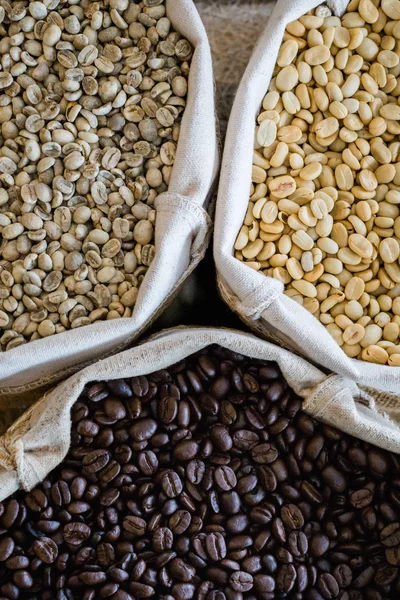 Yeşil ve kahverengi kahve çekirdekleri kavrulmamış ve siyah kahve çekirdekleri çuvalda.