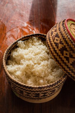 Buharda pişmiş pirinç hasır sepetin içinde, ahşap masada..