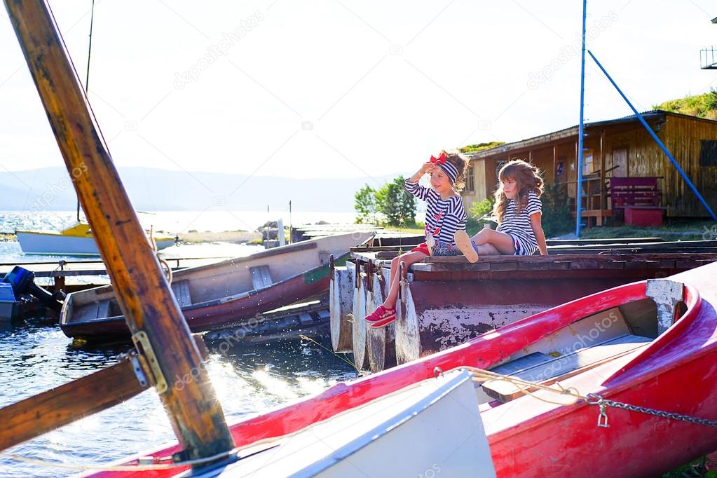 Two young girls sitting on the dock, laughing and smiling, looking around
