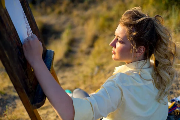 Young artist draws a seascape at sunset — Stock Photo, Image
