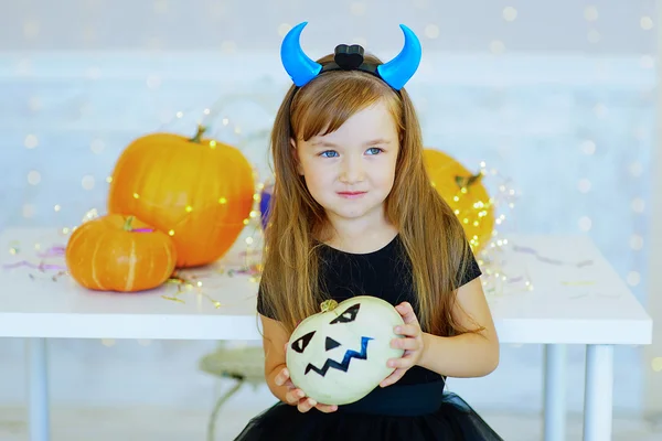 Little girl in demon costume playing with pumpkins — Stock Photo, Image