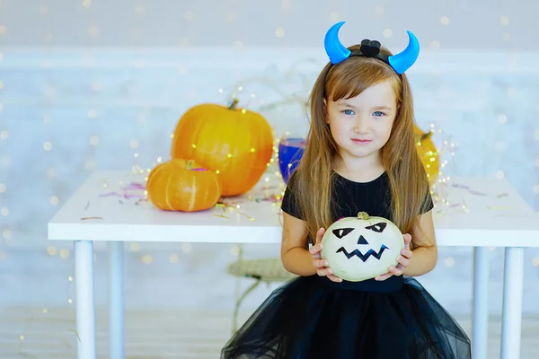 Little girl in demon costume playing with pumpkins — Stock Photo, Image