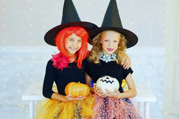 Dos niñas en traje de bruja jugando con calabazas —  Fotos de Stock