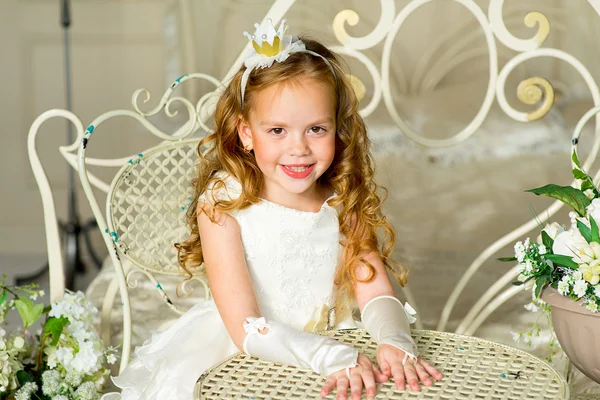Маленькая принцесса сидит рядом со столом — стоковое фото