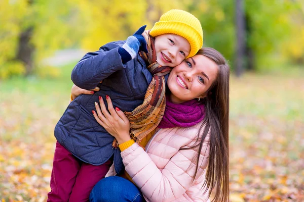 Boy hugs his mother in autumn park — Stock Photo, Image