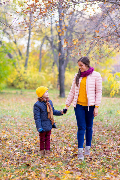 boy walking with his mother in autumn park