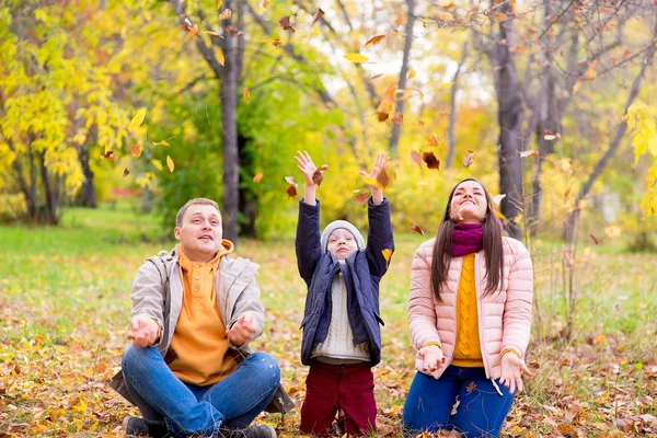 Familia jugando con hojas otoño parque — Foto de Stock