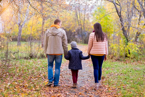 Family of three walks in the autumn park — Stock Photo, Image