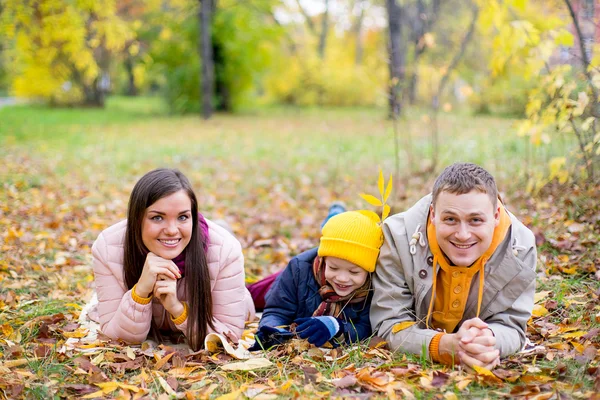 family lying on the leaves autumn park