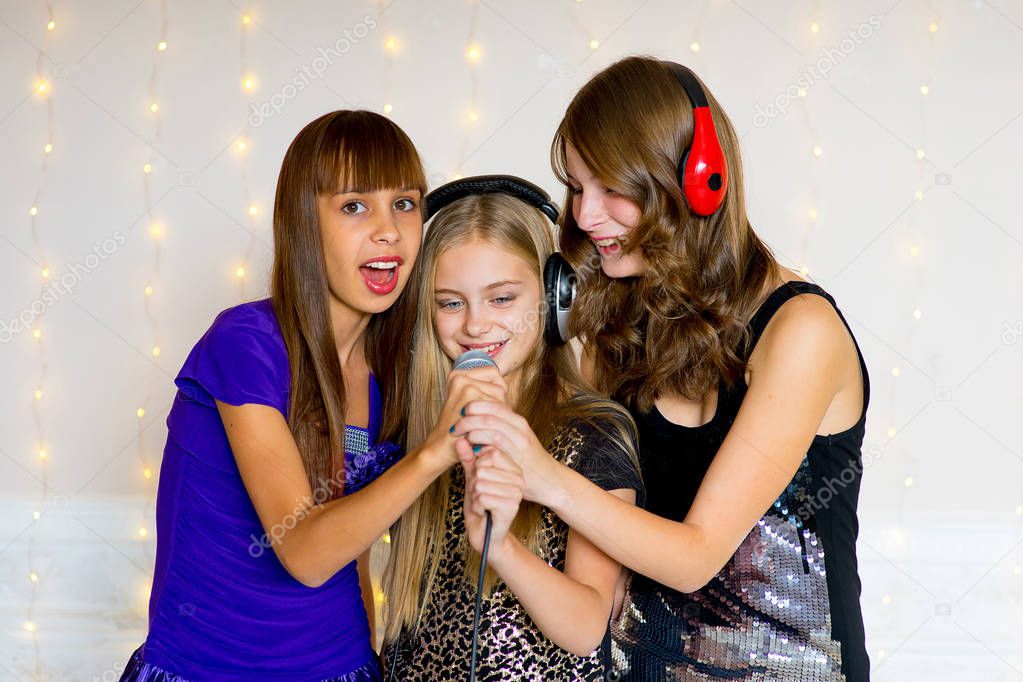 Group of happy girls singing on karaoke