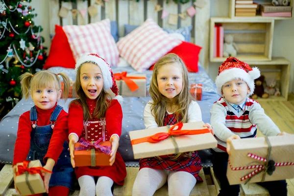 Gruppo di bambini in cappello rosso con regali di Natale — Foto Stock