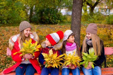 group of girls in autumn park on the brench clipart