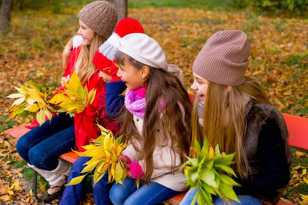 Group of girls in autumn park on the brench — Stock Photo, Image