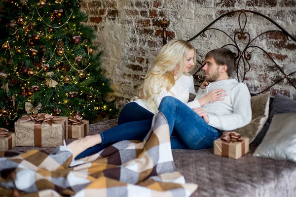 O par feliz de amantes em suéteres brancos dá presentes um ao outro — Fotografia de Stock