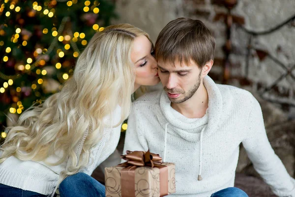 Šťastný pár milenců v bílých pulovry dávají navzájem dárky — Stock fotografie