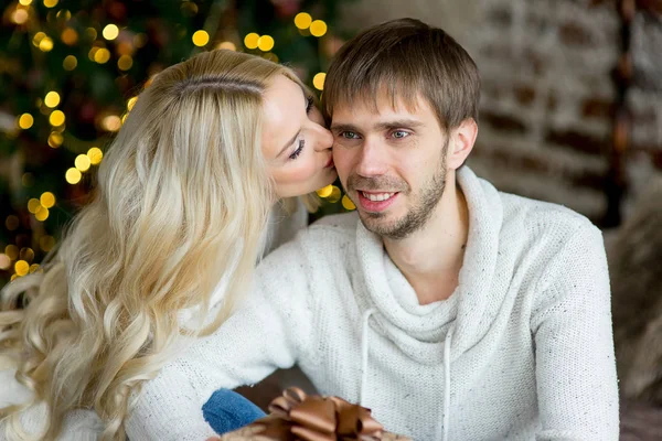 Šťastný pár milenců v bílých pulovry dávají navzájem dárky — Stock fotografie