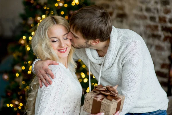 Šťastný pár milenců v bílých pulovry dávají navzájem dárky — Stock fotografie
