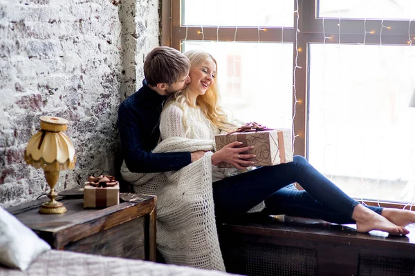 Casal feliz de amantes em pulôveres dar uns aos outros presentes sentados — Fotografia de Stock