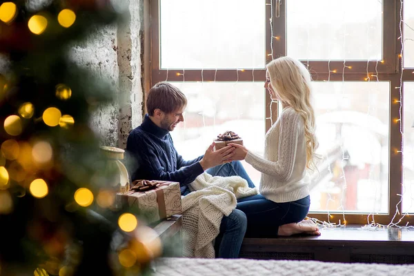 Счастливая пара влюбленных в пуловеры дарить друг другу подарки сидя — стоковое фото