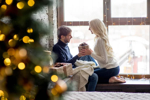 Glückliches Liebespaar in Pullovern beschenkt sich sitzend — Stockfoto