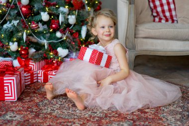 ağacın yanında oturan Noel hediye ile küçük kız