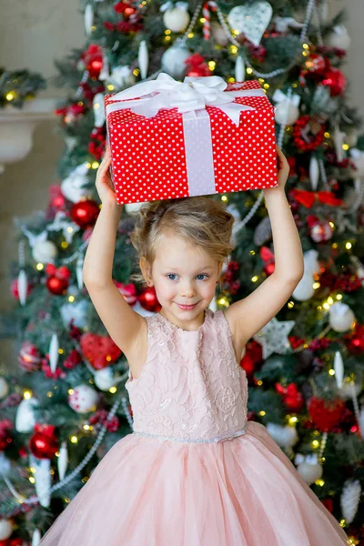 Meisje met de gift van Kerstmis zitten in de buurt van boom — Stockfoto