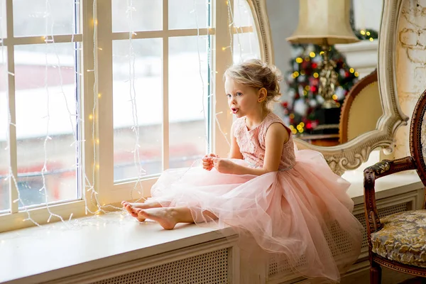 Милая маленькая девочка сидит у окна — стоковое фото
