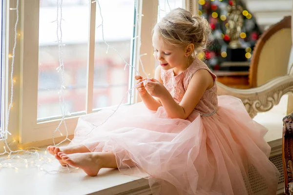 Cute little girl sitting by the window — Stock Photo, Image