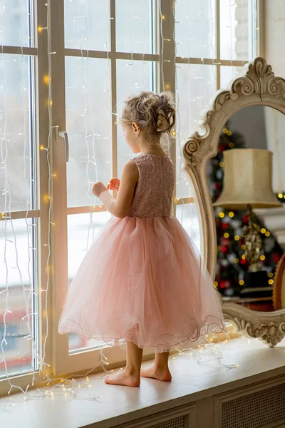 Χαριτωμένο μικρό κορίτσι, στέκεται δίπλα στο παράθυρο — Φωτογραφία Αρχείου