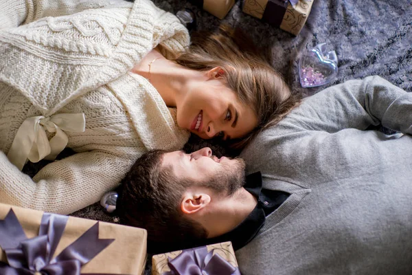 Casal feliz de amantes deitado entre presentes de Natal — Fotografia de Stock