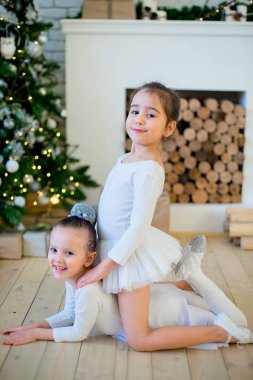 Noel ağacının yanında oturan iki genç bale dansçısı